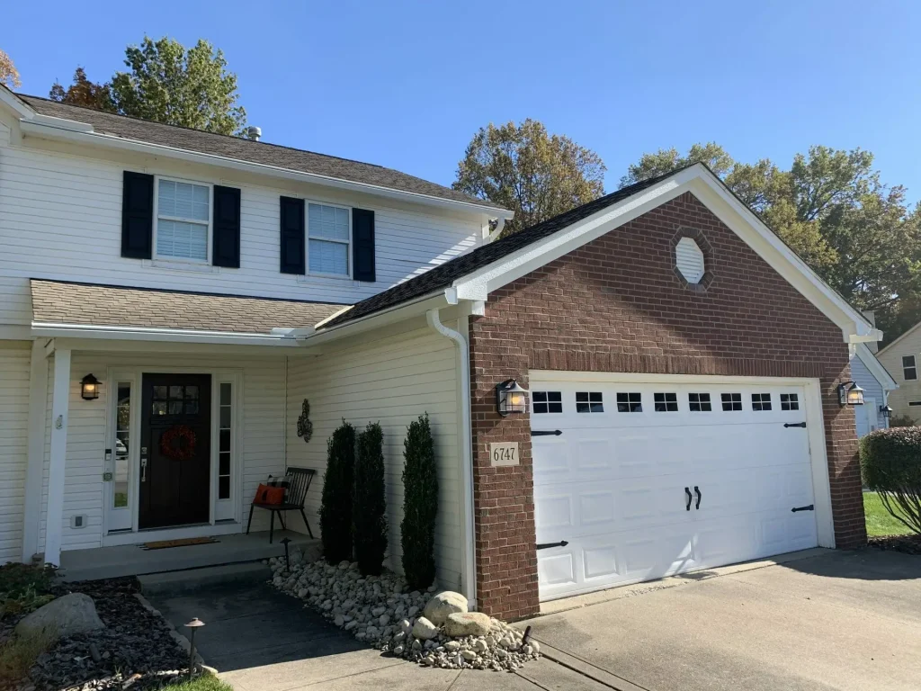 White home with a brick garage and K-Guard gutters